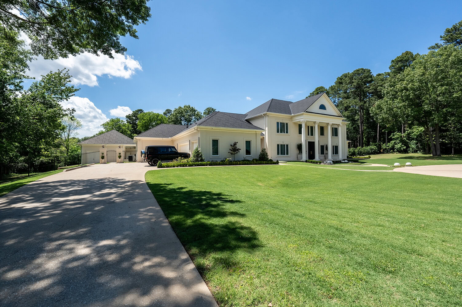 Beautiful white house with columns and a spacious lawn under a blue sky.
