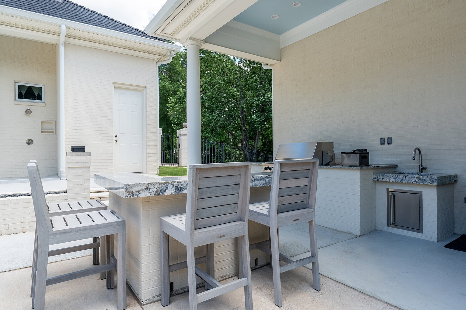 Modern outdoor kitchen with bar seating and grill at The Thornwood.