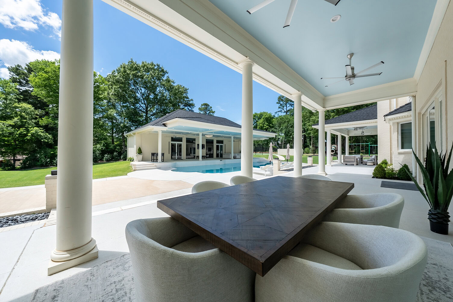 Elegant outdoor patio with pool, seating area, and lush greenery.