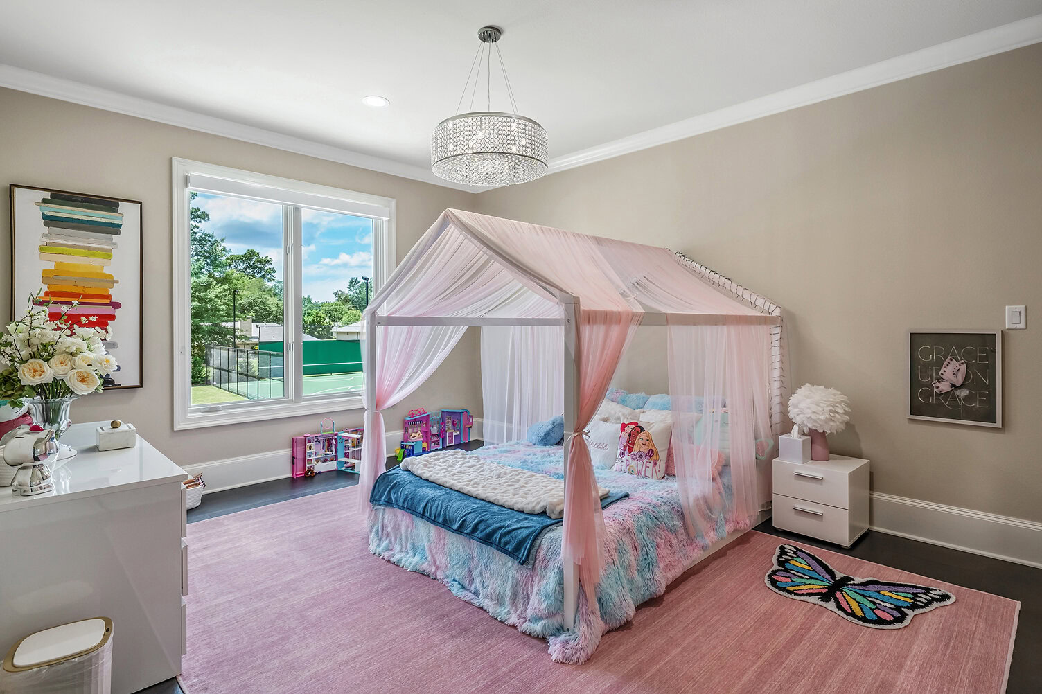 Bright children's bedroom with pink canopy bed and colorful decor.