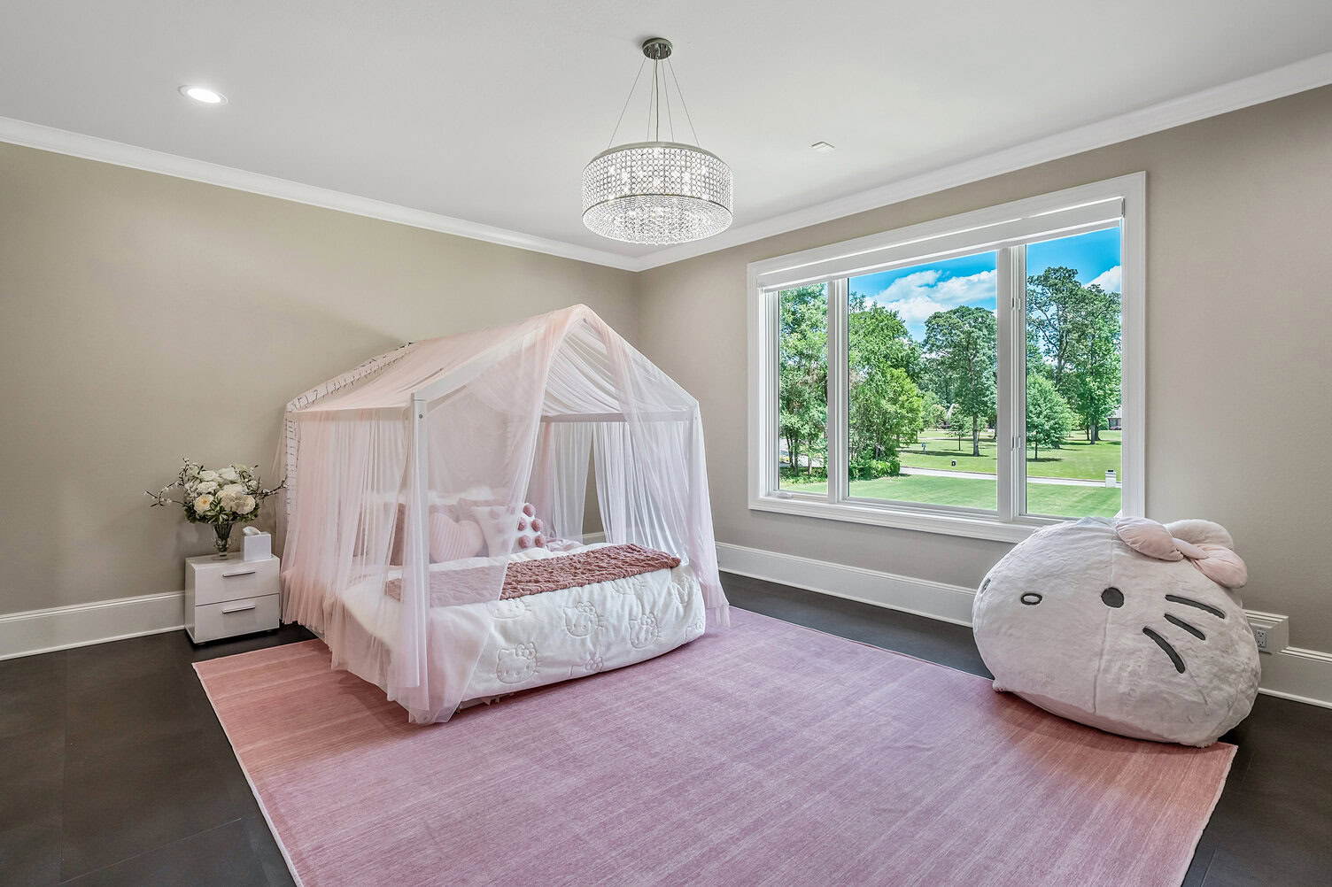 Bright bedroom with canopy bed and large window overlooking green landscape.