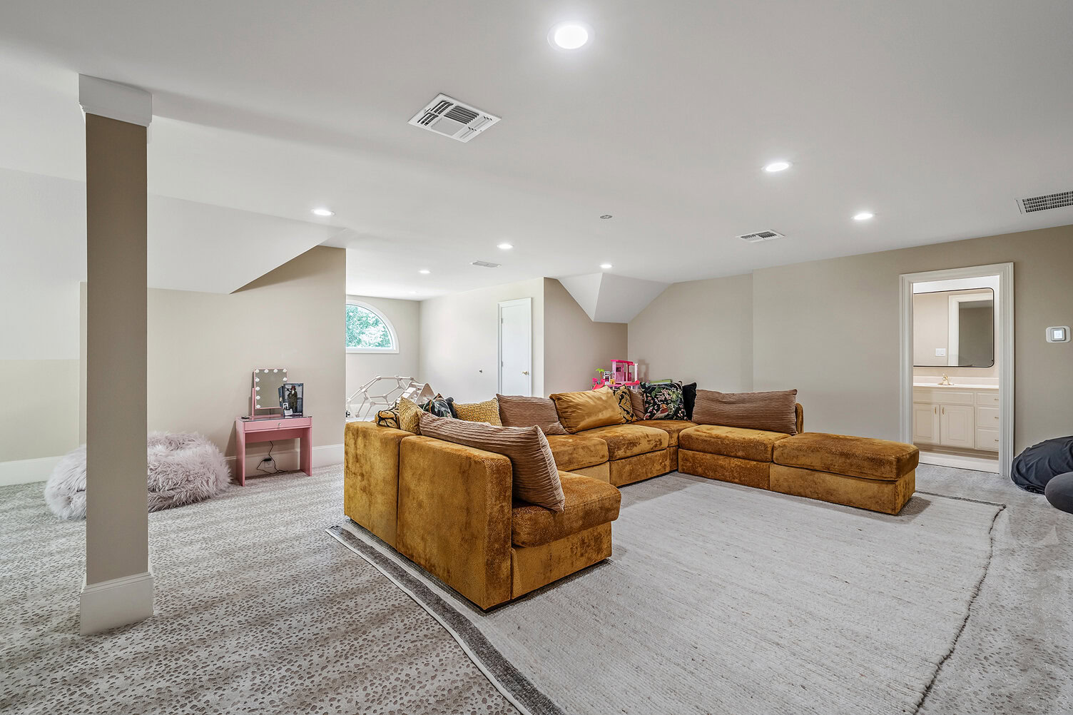 Bright basement living room with large sectional sofa and neutral decor.