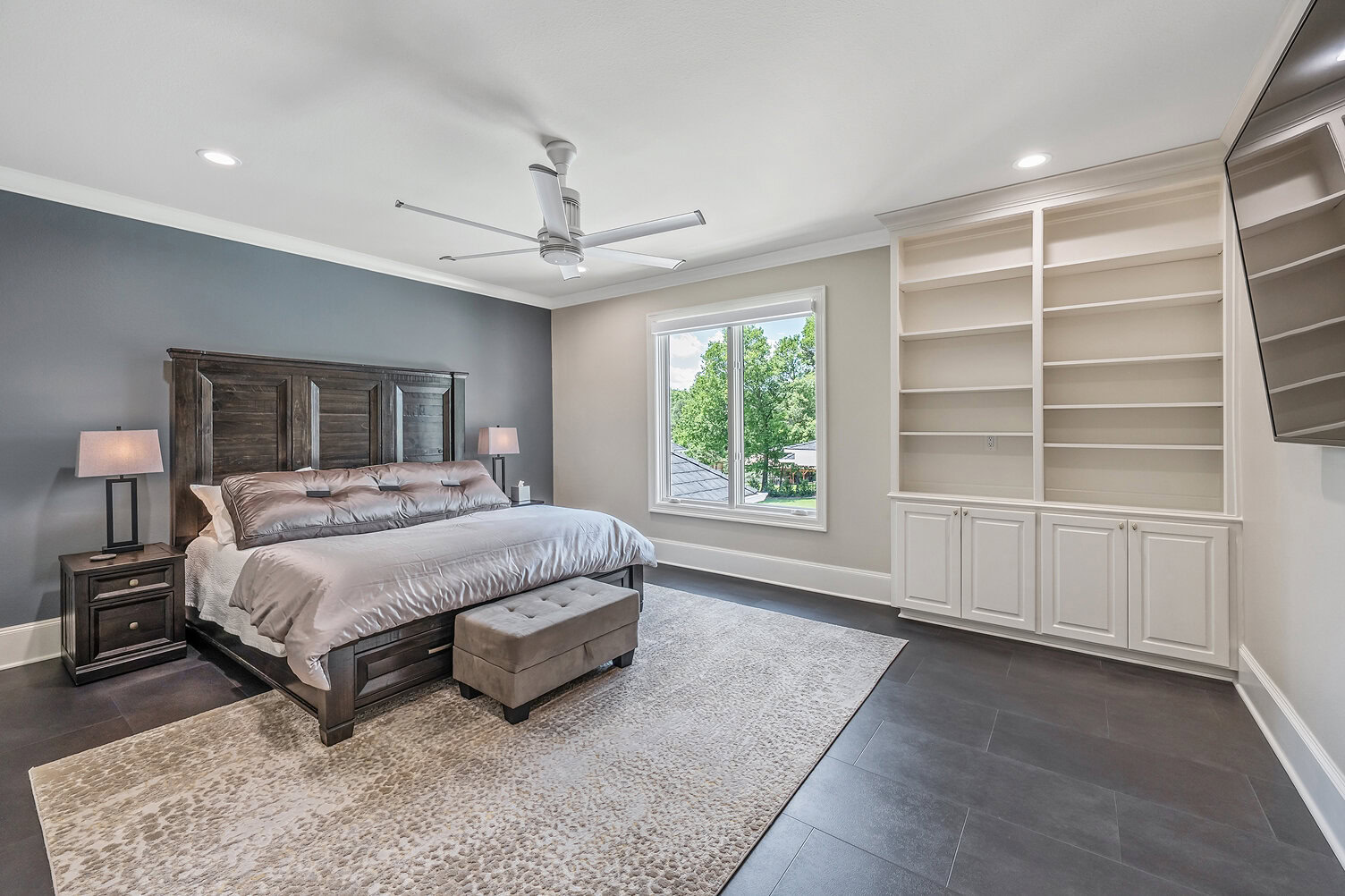 Spacious bedroom with large window, built-in shelves, and contemporary decor.