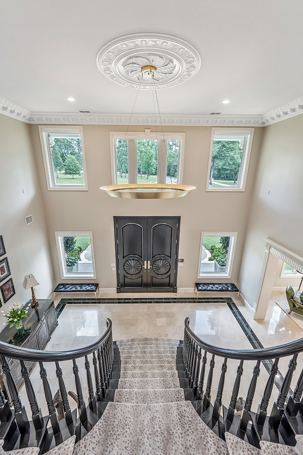 Spacious and luxurious foyer with grand staircase and chandelier.
