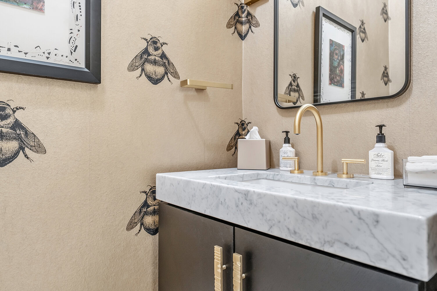 Bathroom with bee-themed wall art and elegant marble sink.