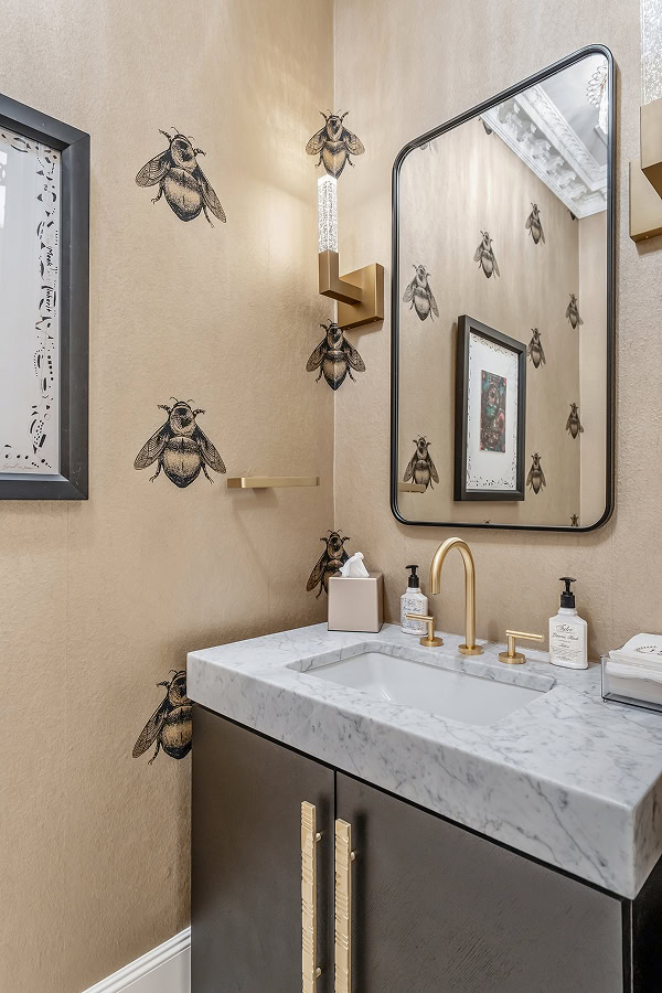 Bathroom with bee wall art, mirror, and marble sink.