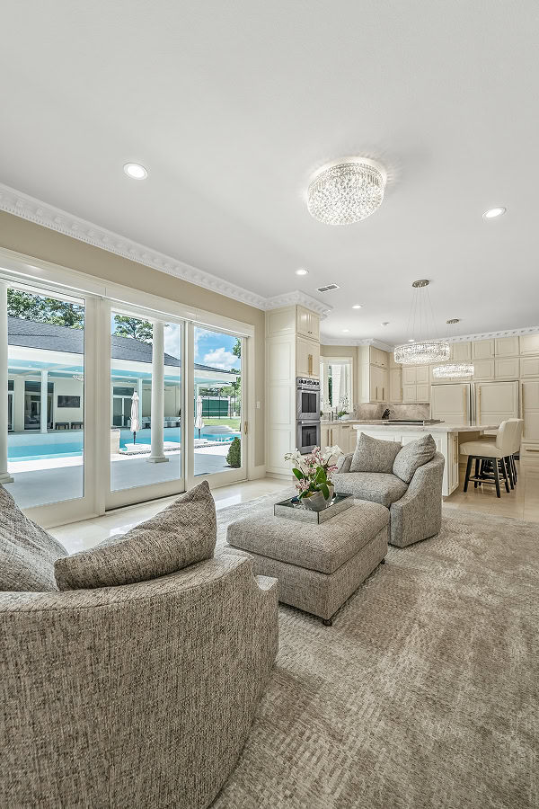 Bright living room with large windows overlooking pool area.