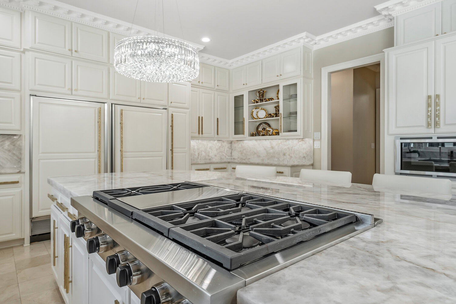 Elegant white kitchen with marble countertops and modern appliances.