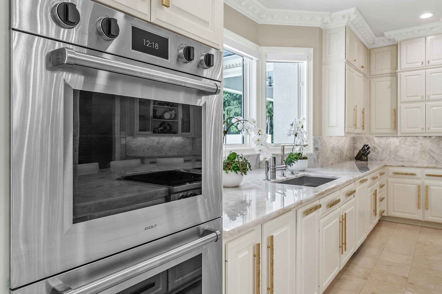 Bright kitchen with stainless steel oven and white cabinets.