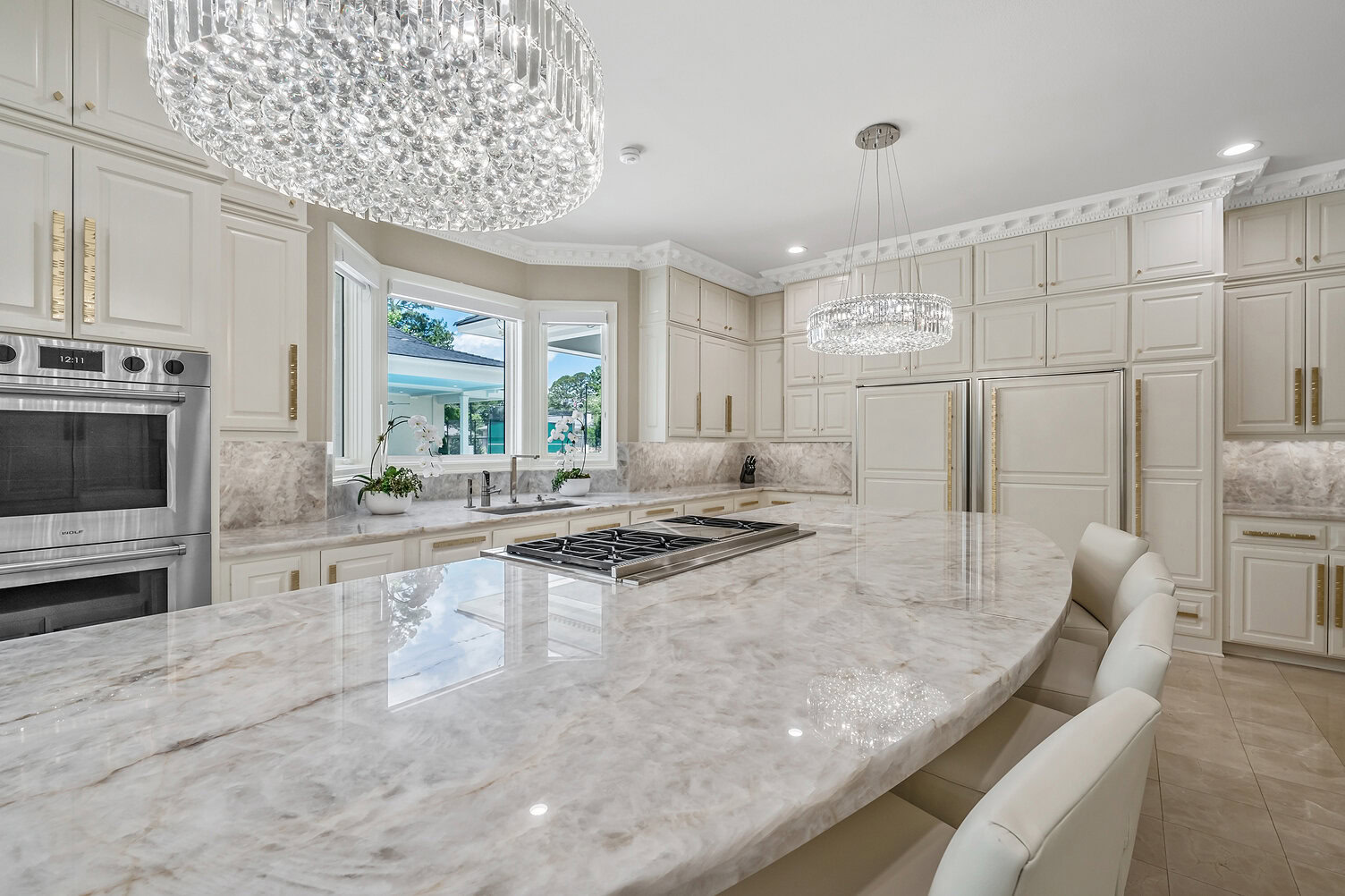 Spacious kitchen with marble countertops, white cabinets, and modern lighting fixtures.