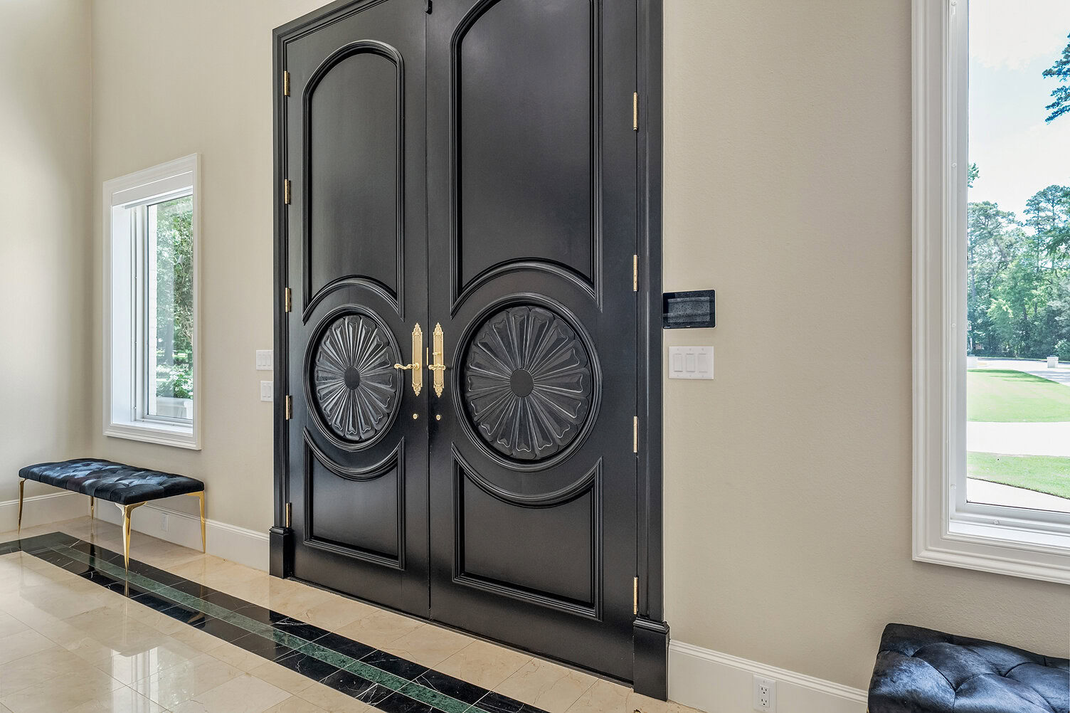 Stylish black double doors with gold handles in a modern home entrance.