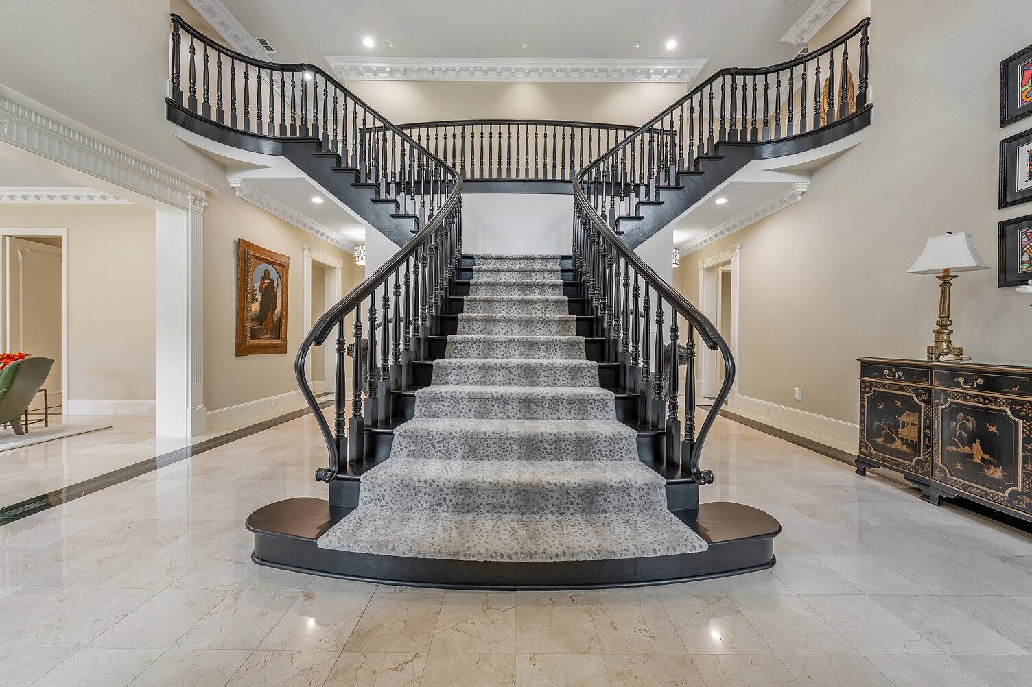 Luxurious double staircase with black railings and gray carpet at The Thornwood.