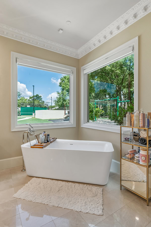 Bright bathroom with large windows and a white freestanding bathtub.
