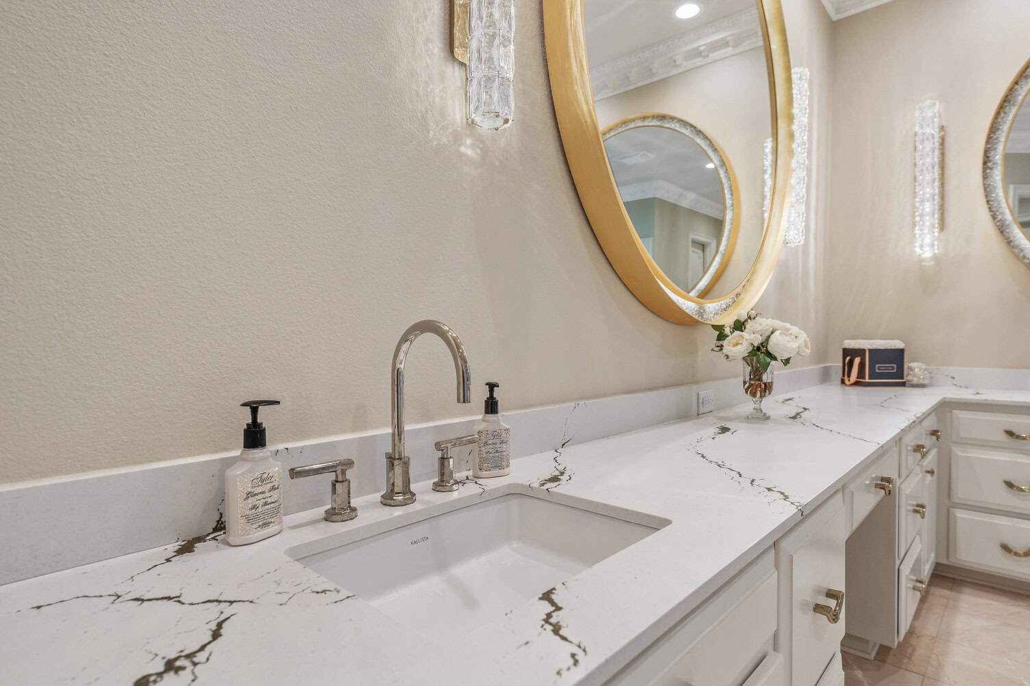 Modern bathroom with marble countertop, round mirror, and elegant decor.