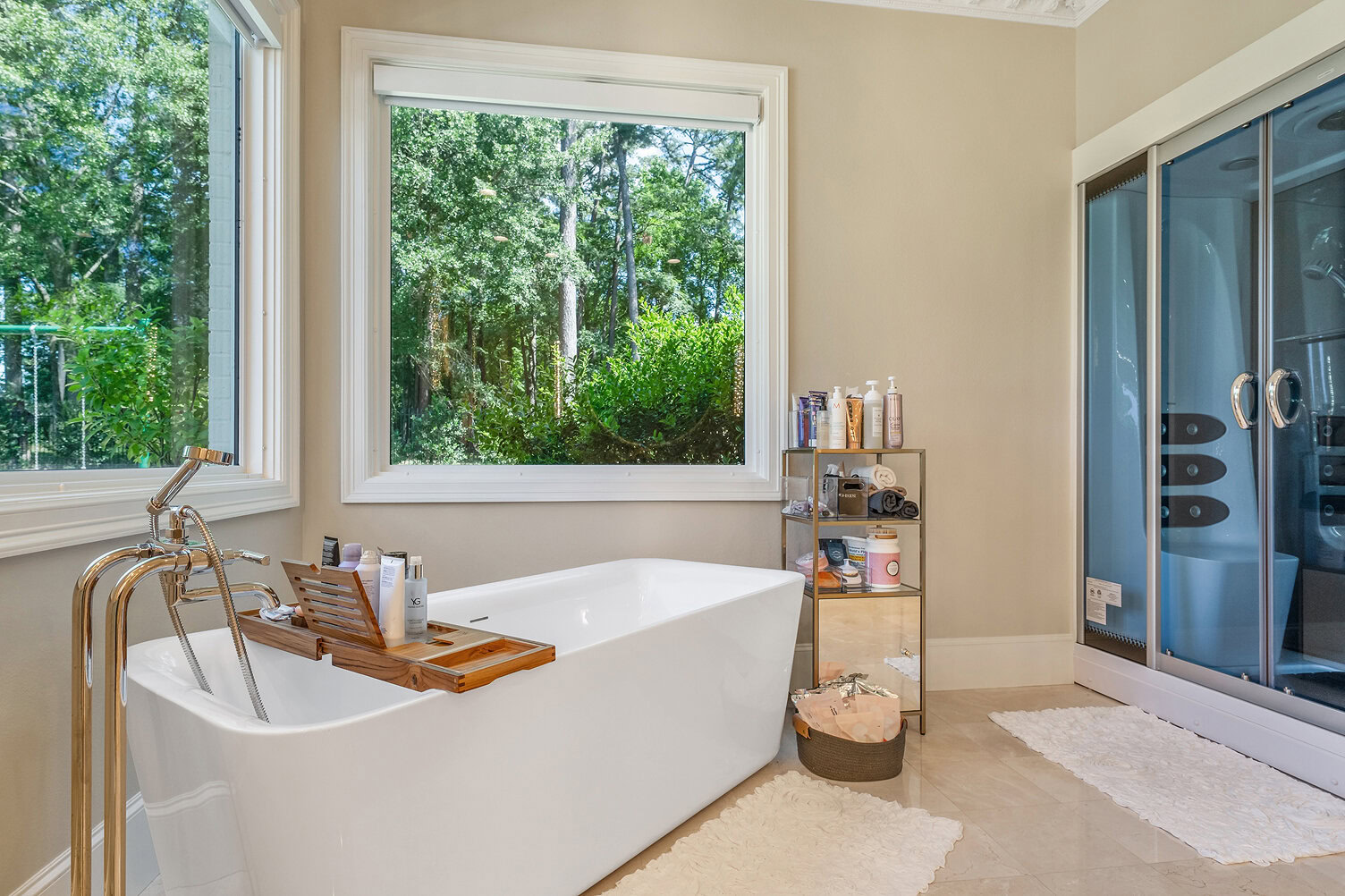 Bright bathroom with large window, freestanding tub, and glass shower enclosure.