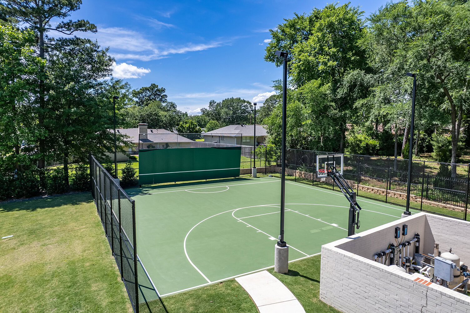 Outdoor basketball court with fencing and surrounding trees at The Thornwood.