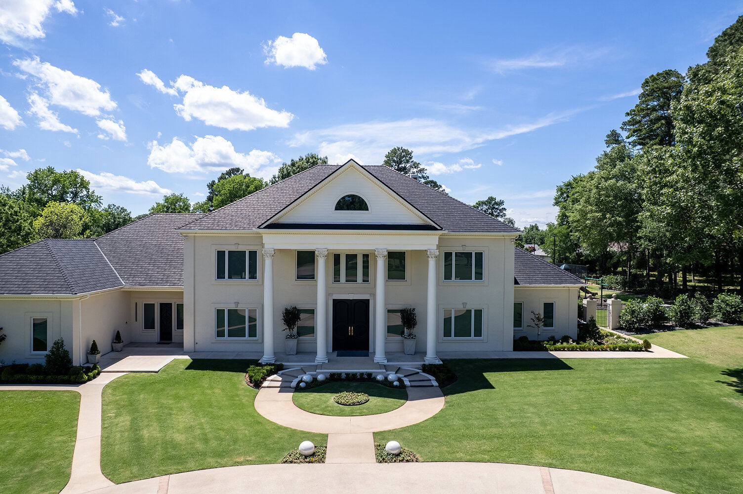 Elegant white mansion with grand columns and lush green lawn in The Thornwood.