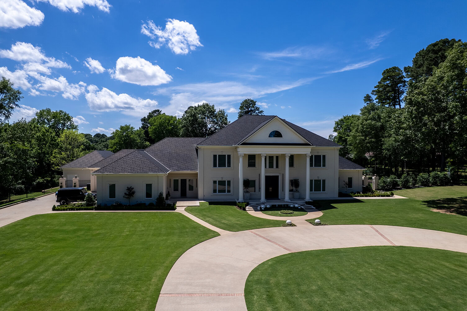 Elegant white mansion with large lawn and curved driveway in The Thornwood.
