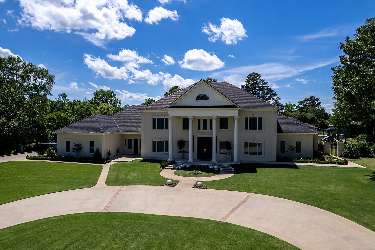 Elegant mansion with grand entrance and lush landscaping in The Thornwood.